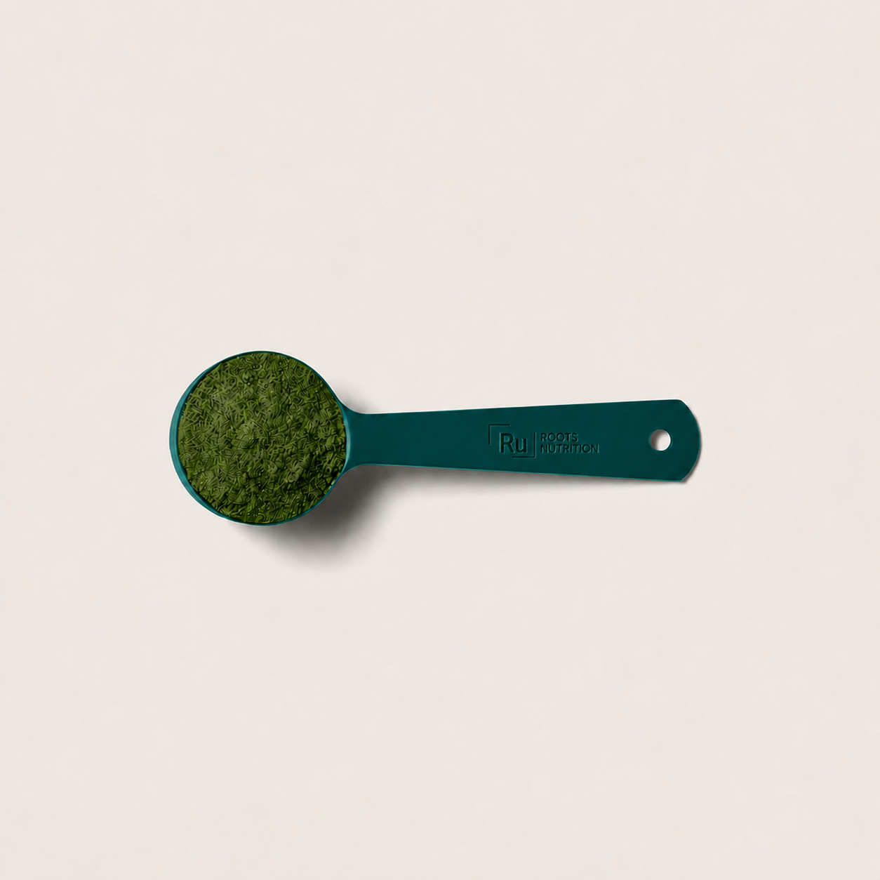 Teal measuring spoon with green powder on a beige background